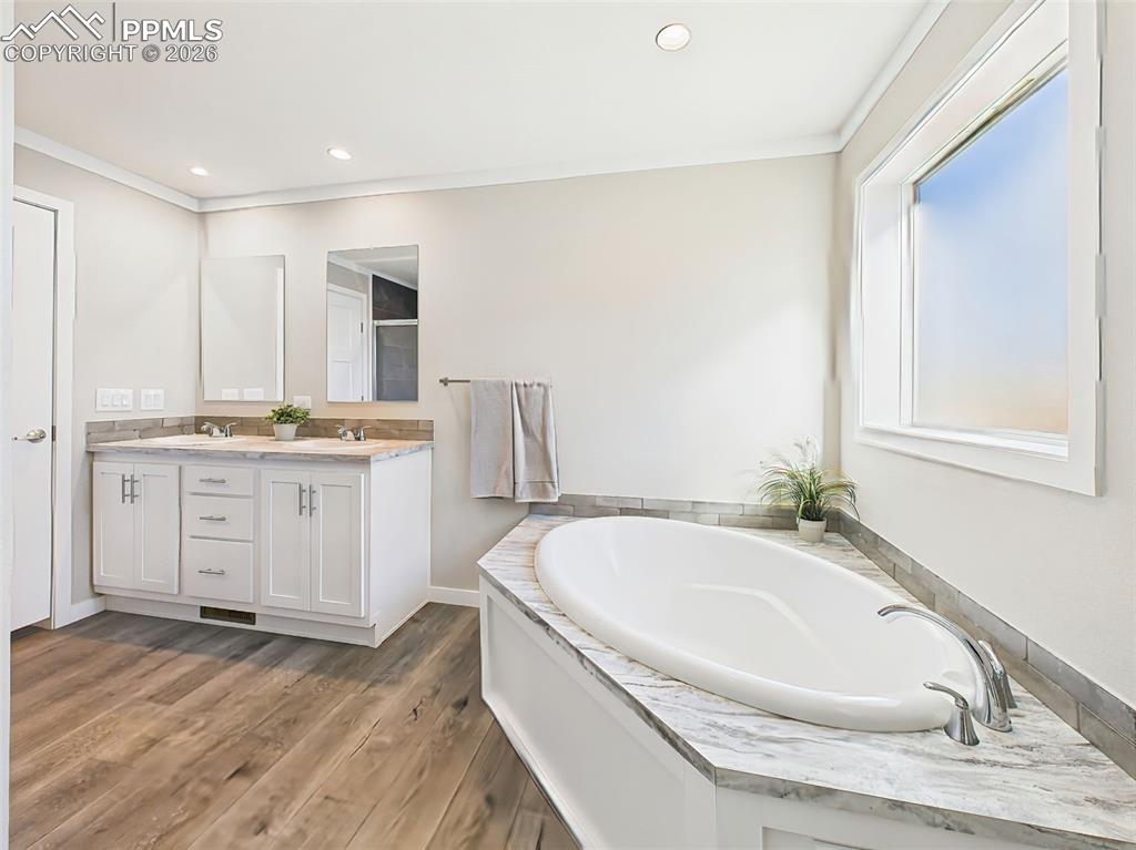 Primary Bath Soaking Tub – An angled view of the deep soaking tub beneath a large frosted window adds to the spa-inspired feel of this relaxing retreat.