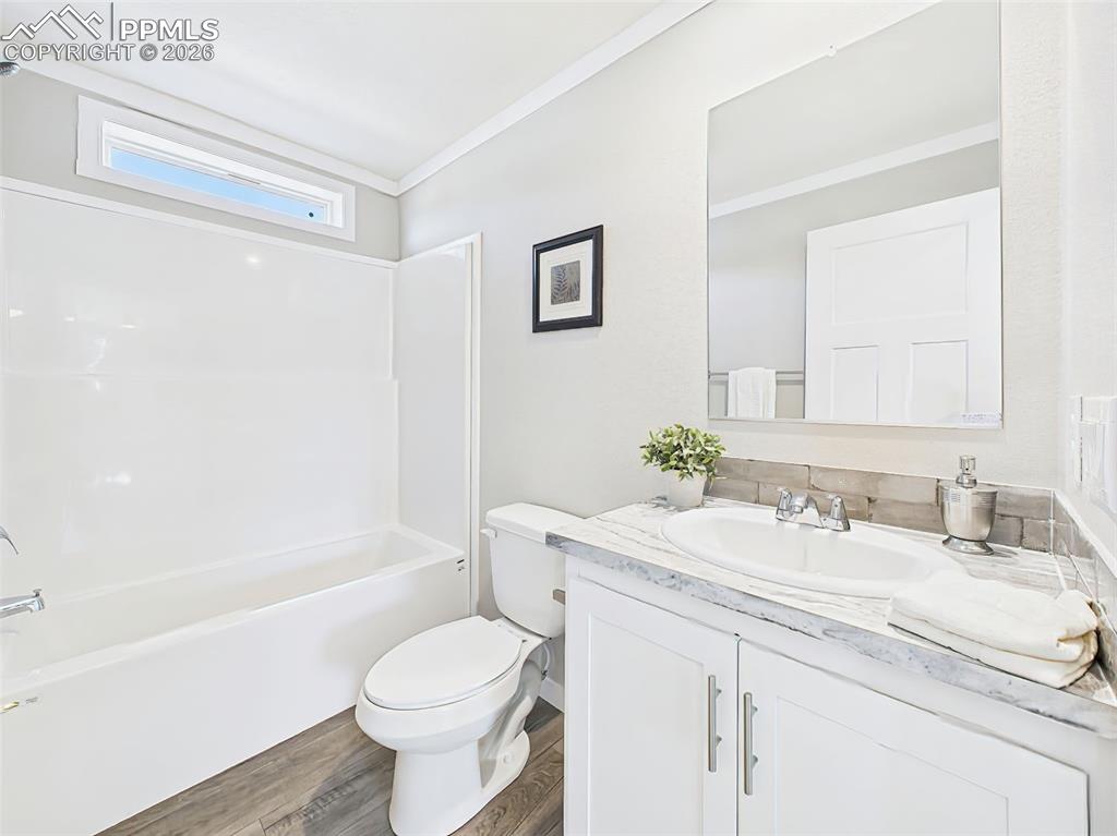 Hall Bathroom – A full bath with a tub-shower combo, sleek tile backsplash, and stylish marble-look counters over white cabinetry.