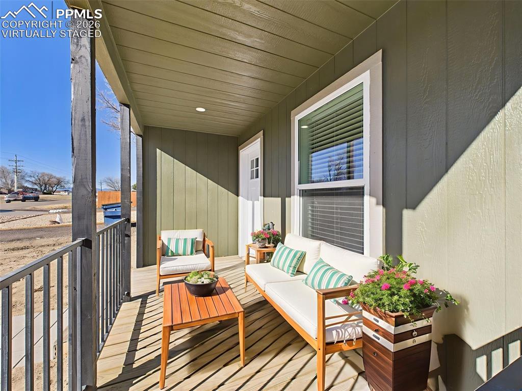 Virtually Staged Front Porch – This cozy front porch is shown with comfortable seating and vibrant planters, offering a sunny spot to relax and unwind.