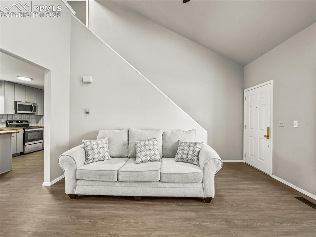 Living room featuring wood finished floors, baseboards, and vaulted ceiling