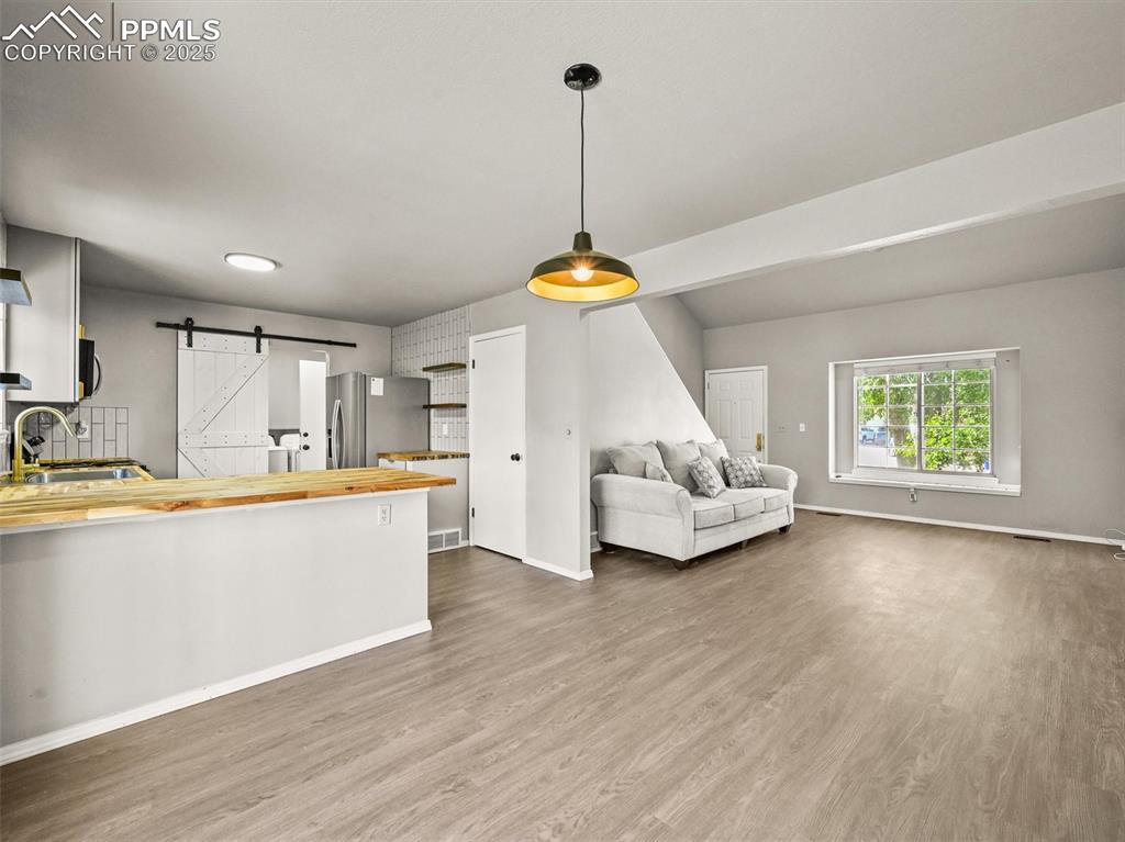 Kitchen featuring a barn door, butcher block counters, dark wood-style flooring, and stainless steel fridge