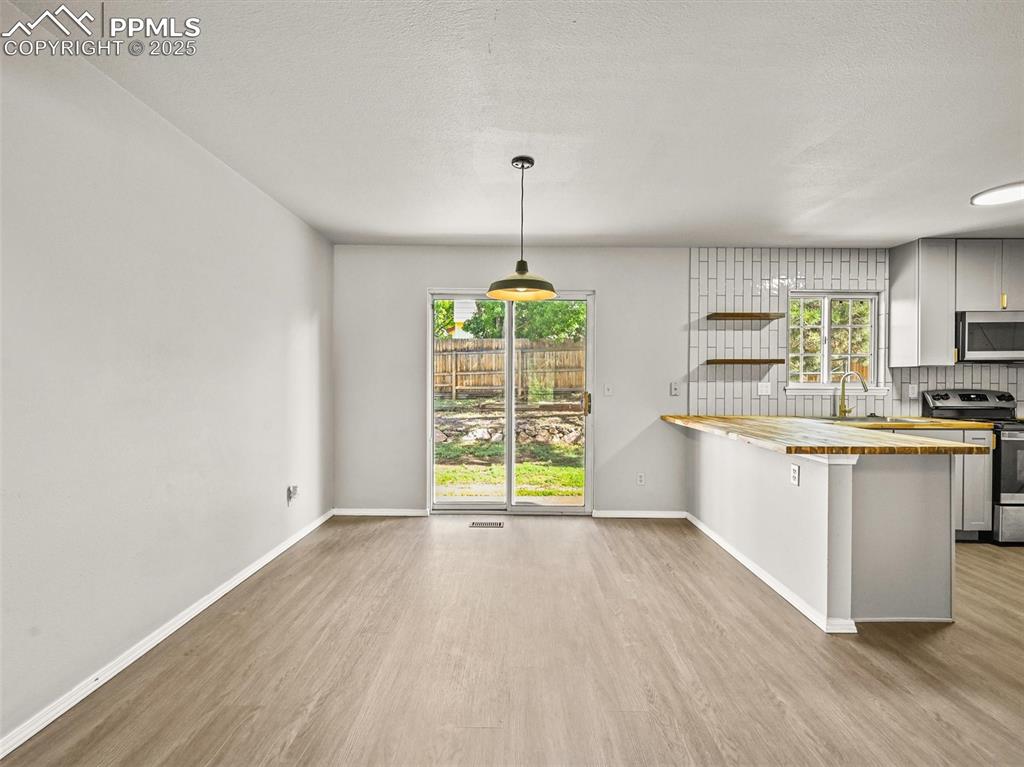 Kitchen featuring appliances with stainless steel finishes, wooden counters, wood finished floors, and a sink