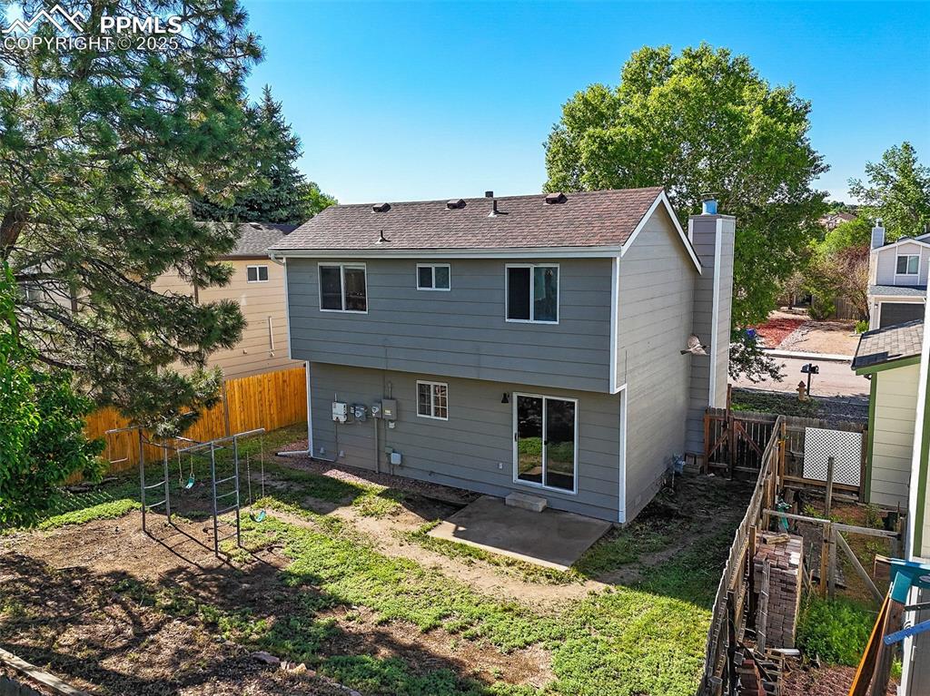 Rear view of house with a patio, a fenced backyard, a chimney, and a shingled roof