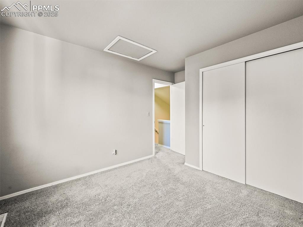 Unfurnished bedroom with attic access, carpet floors, a closet, and baseboards