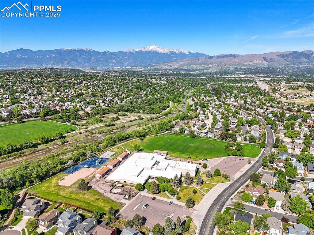 Aerial view of property and surrounding area featuring a mountainous background and nearby suburban area