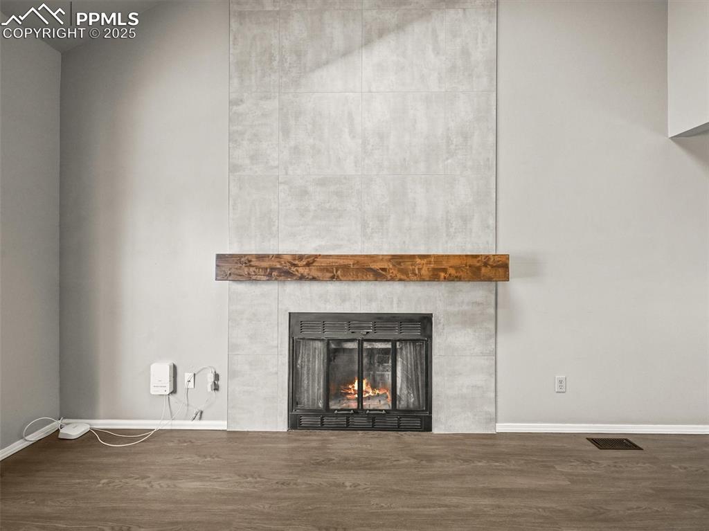 Detailed view of wood finished floors, a fireplace, and baseboards