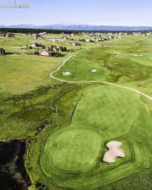 Aerial view of property and surrounding area featuring a golf club and a mountain backdrop.