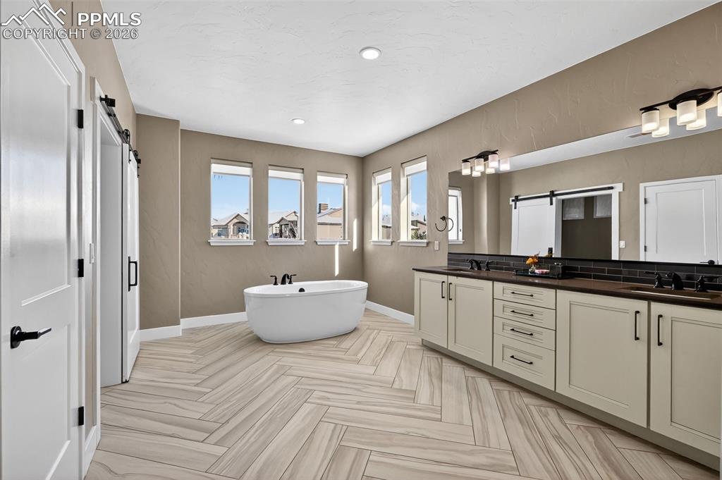 master bath with standalone bathtub, double vanity, shower