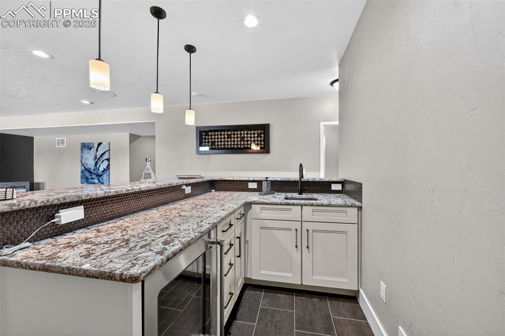 wet bar in lower level includes sink, beverage refrigerator and plenty of seating and storage