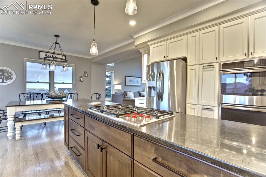 Another view of the kitchen showing one of two islands, GE Profile stainless steel double ovens, refrigerator with water dispenser, Wolf gas cook top w/five burners and hardwood floors.  Open to the light filled Dining Area.