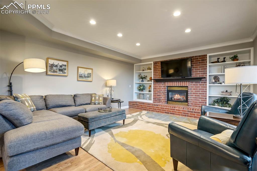 Spacious family room with built in shelves, brick surround, gas fireplace, recessed lighting and hardwood floors.