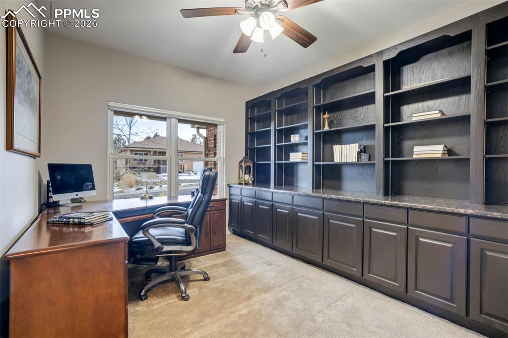 Main floor large office with built-in cabinets and shelving.  Ceiling fan w/lights and carpet. 