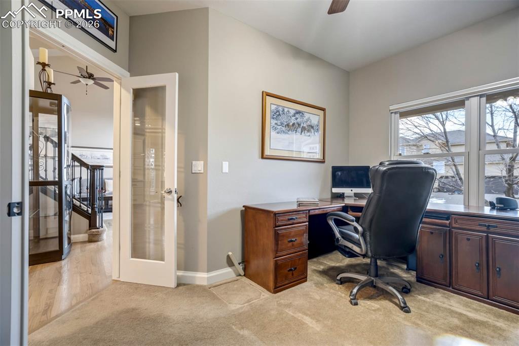 Another view of the main floor office featuring ceiling fan, french doors, and light colored carpet.  This office is perfect for working from home as it is close to the front door and has french doors that can be closed as needed.