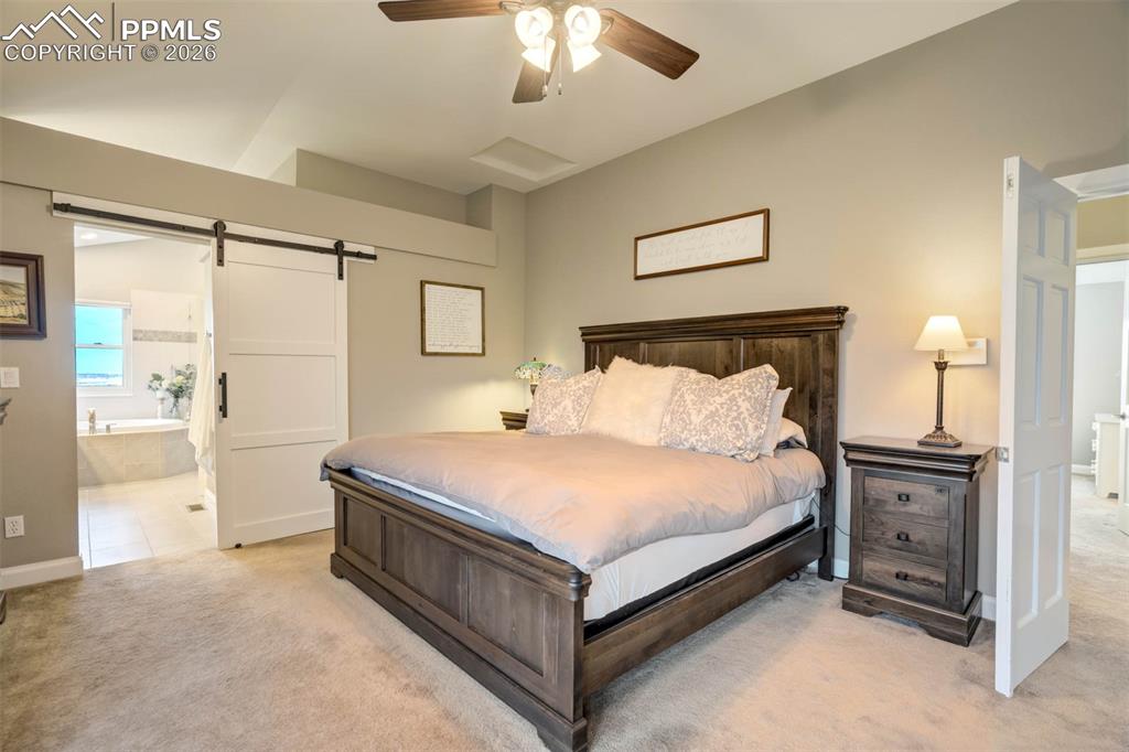Another view of the primary bedroom showing the barn door into the primary bathroom.  