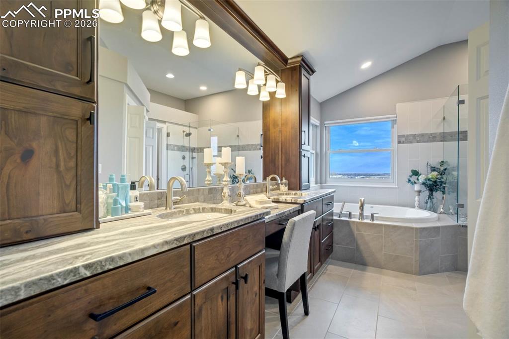 Primary bathroom with marble countertops, double sinks and make-up desk area, large soaking tub, lots of lighting, soaking tub with remote controlled blinds for the windows and a large shower.  There is a separate toilet room and a walk in closet with custom built ins. 