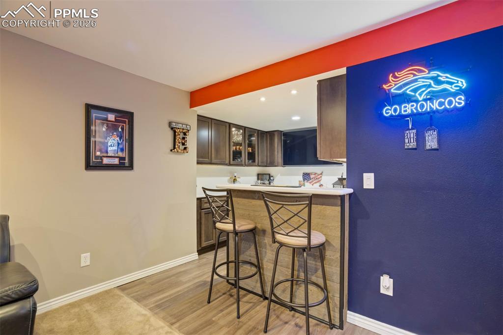  Basement Wet bar with light countertops, glass insert cabinets, and recessed lighting