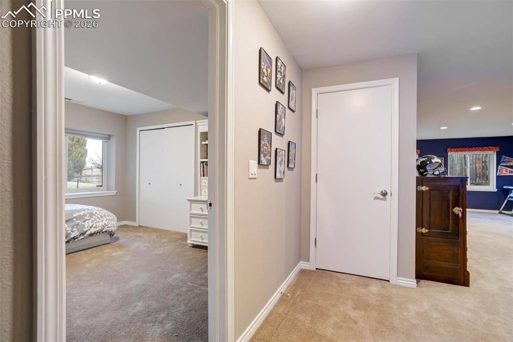 Hallway featuring light colored carpet and baseboards