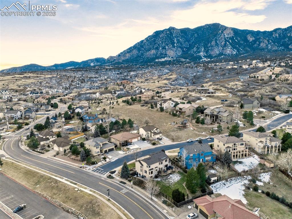 Aerial view at dusk, showing mountain view.  Home is the second home from the bottom right of the image the two story cream with dark roof on the corner lot. 