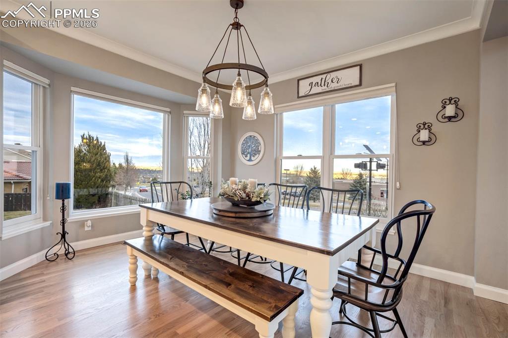 Light filled Dining area featuring hardwood flooring, ornamental molding, lots of windows and a chandelier
