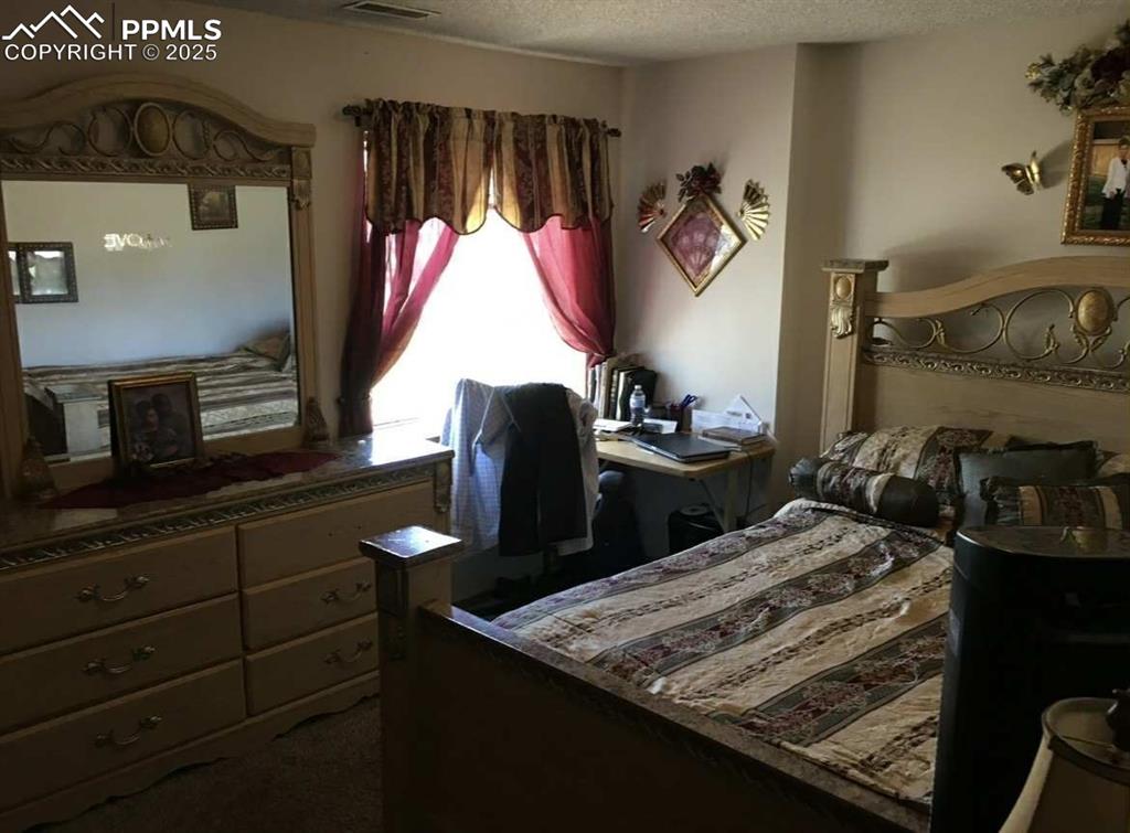 Bedroom with dark colored carpet and a textured ceiling