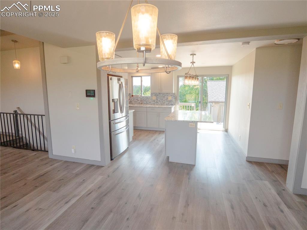 Kitchen featuring stainless steel fridge, backsplash, white cabinetry, and light wood-style floors