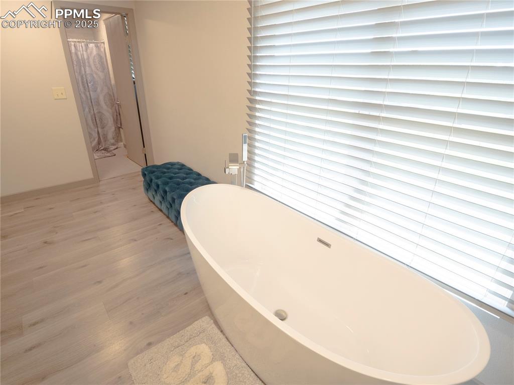 Full bathroom with wood finished floors and a soaking tub