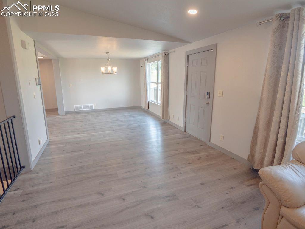 Unfurnished dining area featuring light wood-style floors, a chandelier, vaulted ceiling, and recessed lighting