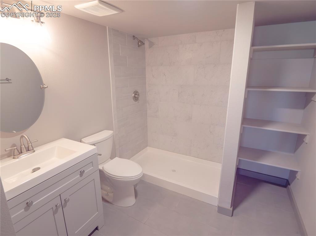 Bathroom featuring vanity, a tile shower, and tile patterned floors