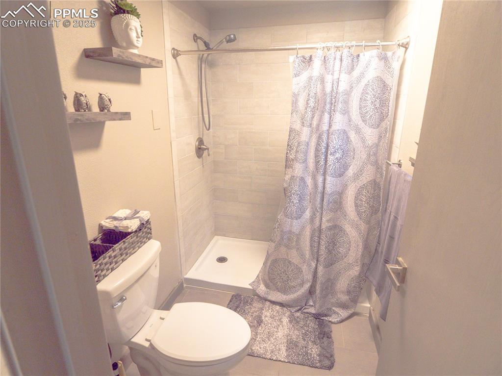 Bathroom featuring tiled shower and toilet