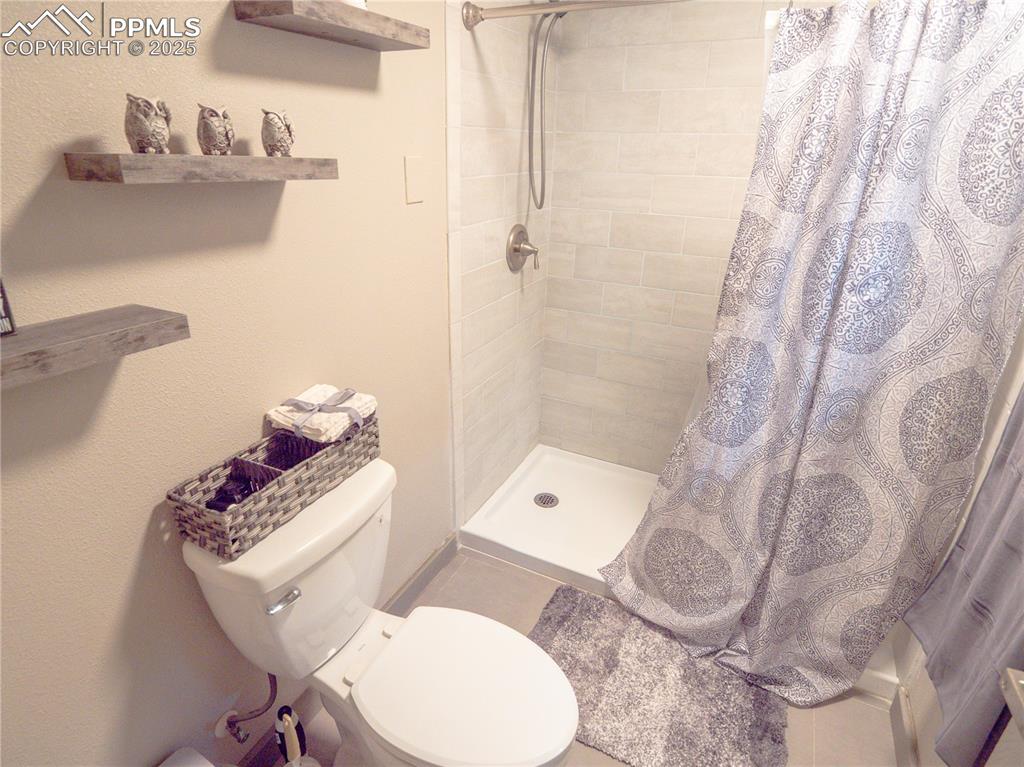 Full bath featuring tiled shower and toilet
