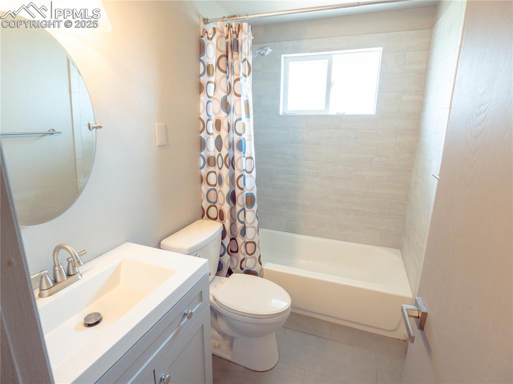 Full bathroom featuring shower / bath combination with curtain, vanity, and tile patterned floors