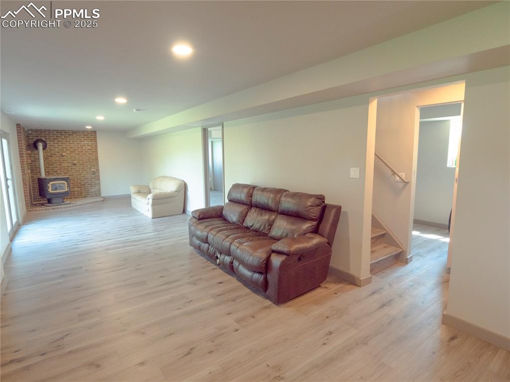 Living room with a wood stove, light wood-style flooring, stairway, and recessed lighting