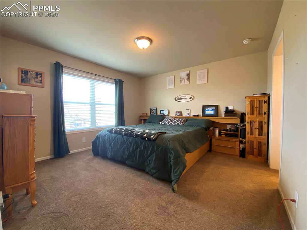 Beautiful main-floor primary suite with a bright, generously sized bedroom and an oversized walk-in closet offering abundant storage and organization