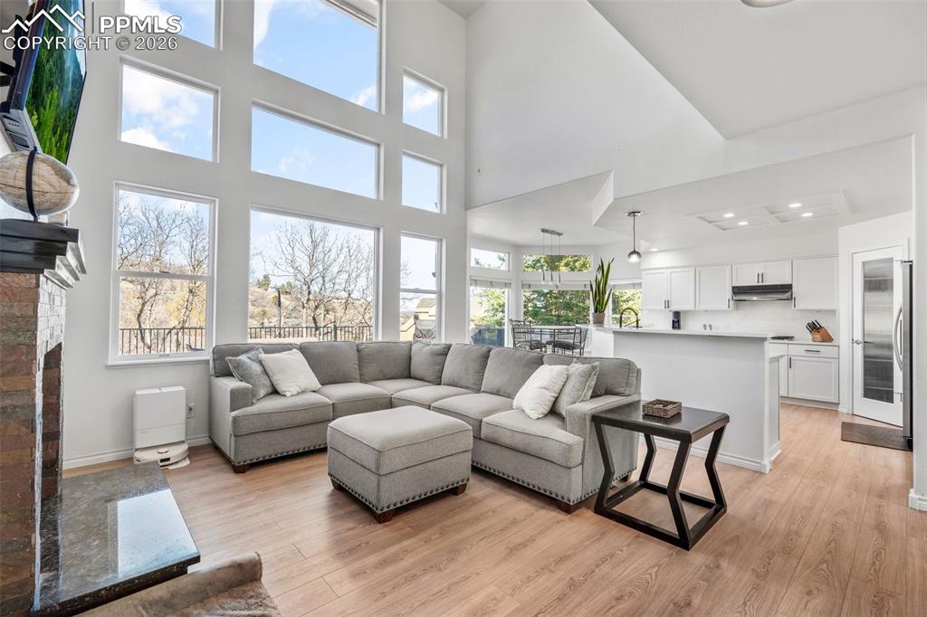 Living area with light wood-style flooring, a fireplace, and a high ceiling
