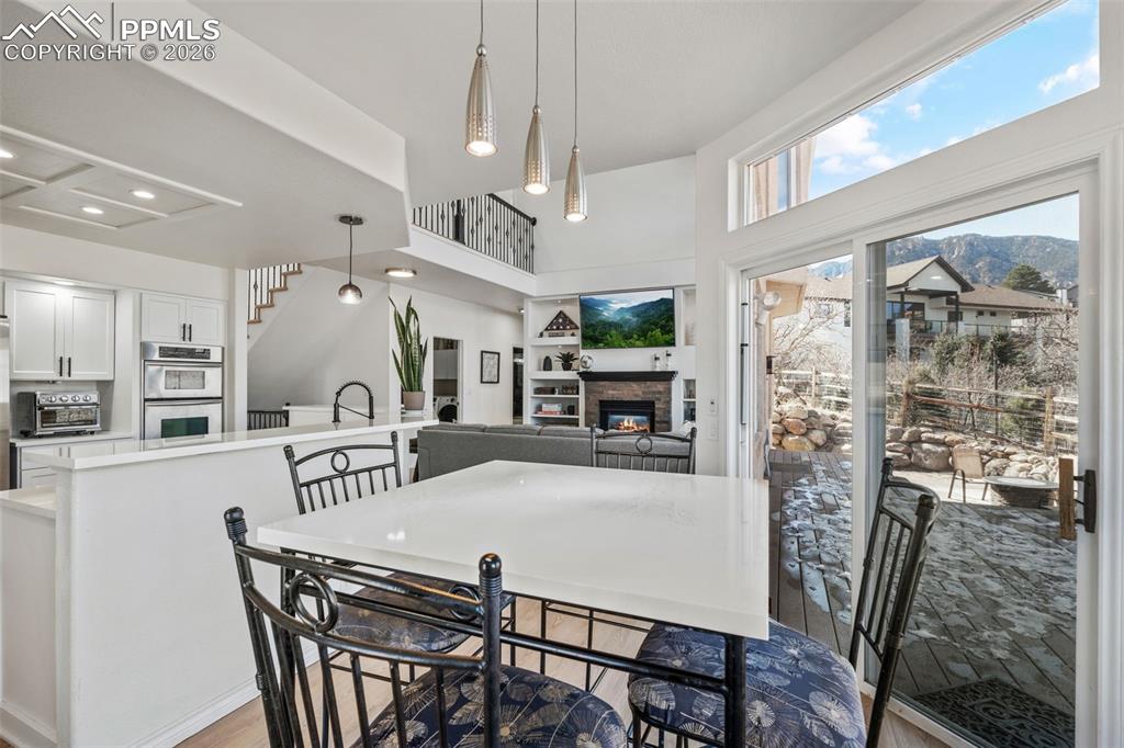 Dining area with a glass covered fireplace, light wood finished floors, plenty of natural light, and a high ceiling