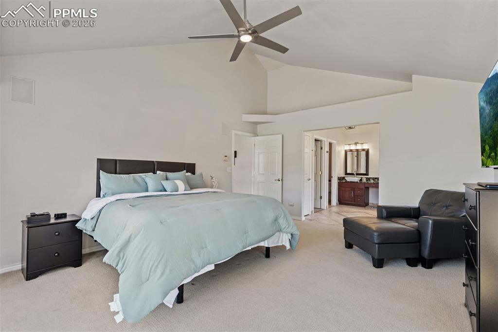 Bedroom featuring light carpet, vaulted ceiling, a ceiling fan, and ensuite bathroom