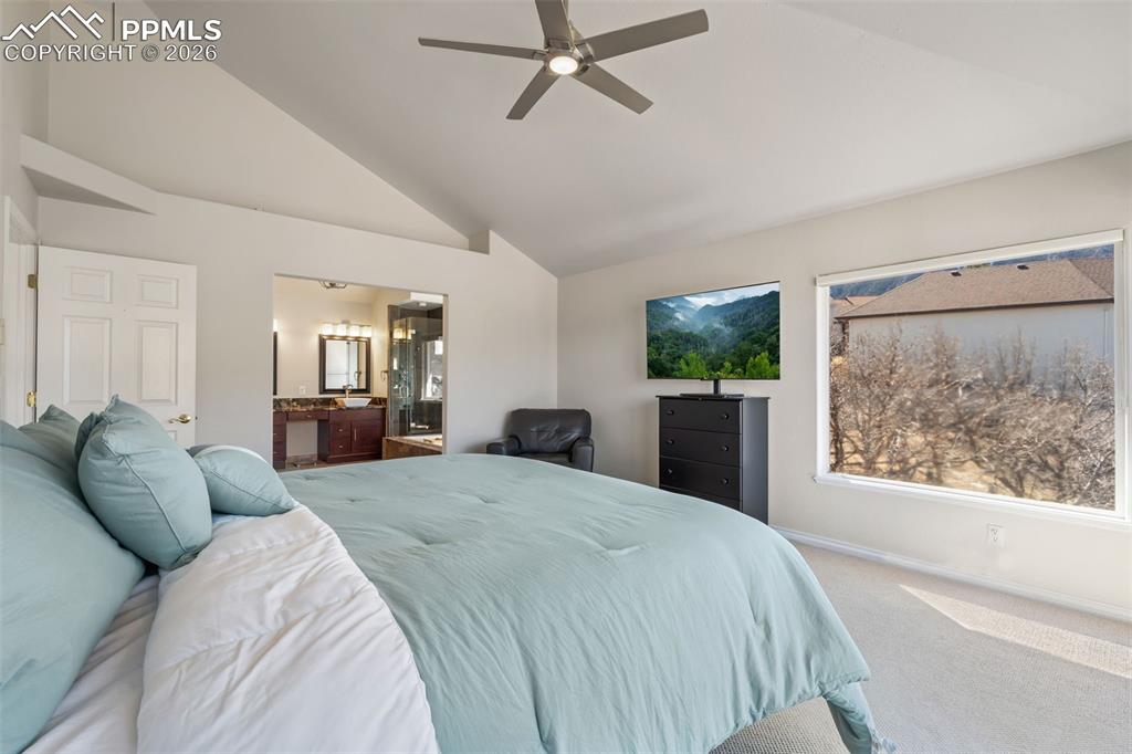 Carpeted bedroom with connected bathroom, lofted ceiling, and a ceiling fan
