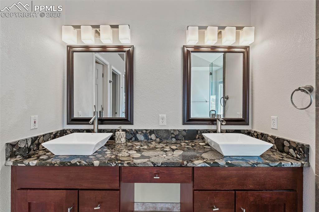 Full bath with double vanity and a textured wall