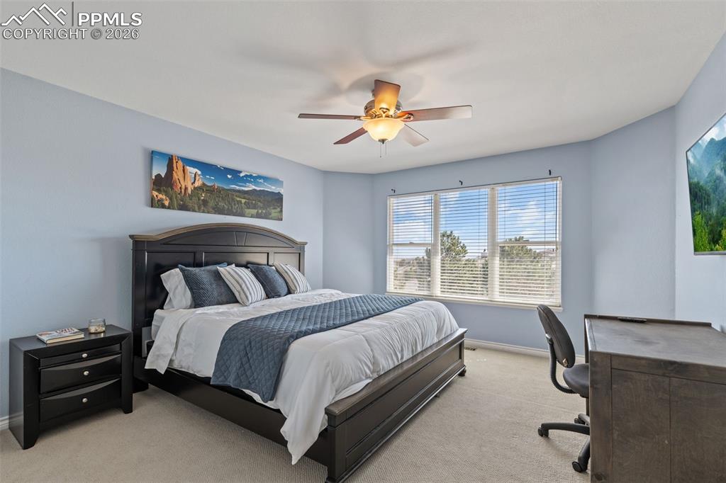 Carpeted bedroom with a desk and a ceiling fan
