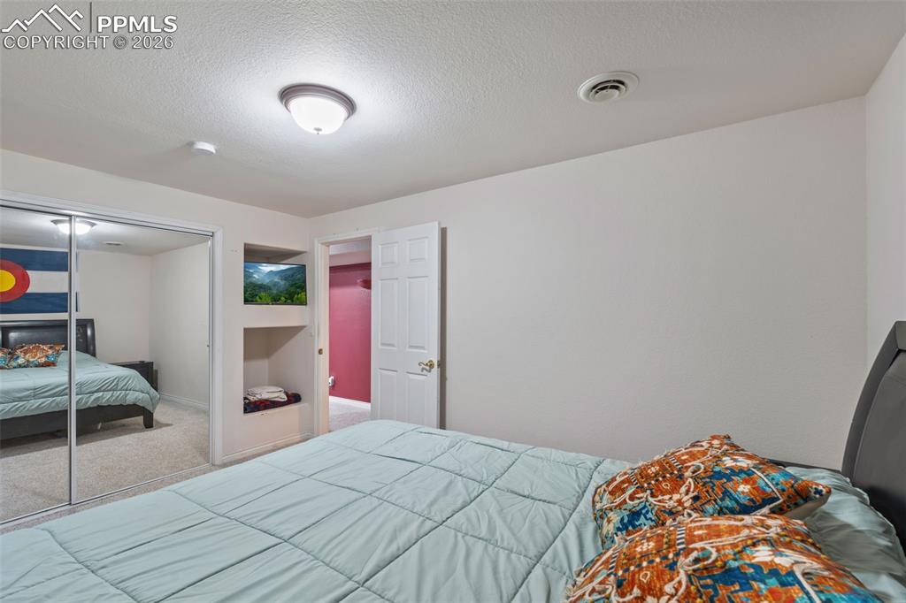 Bedroom with carpet floors, a textured ceiling, and a closet