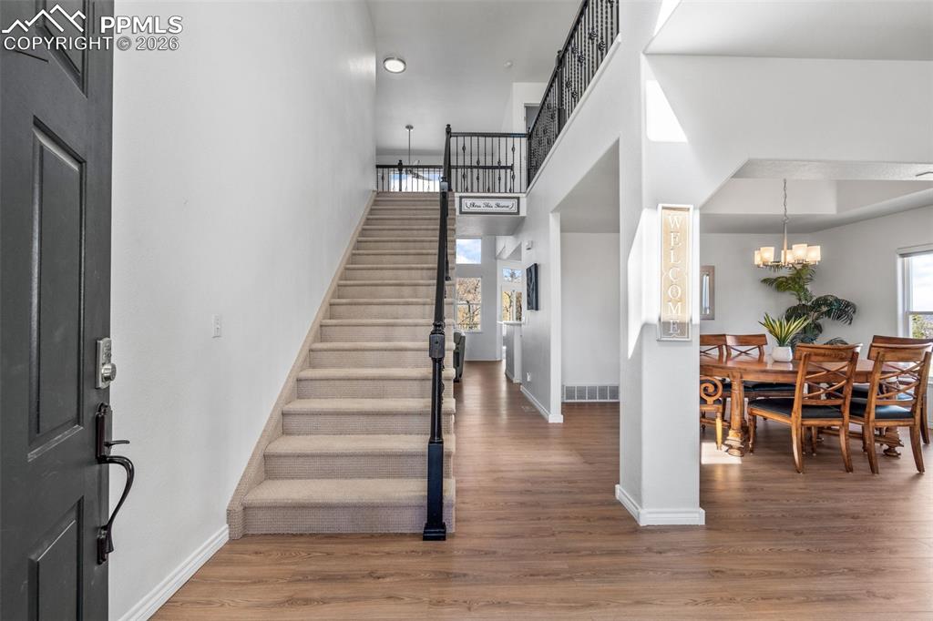 Entryway with wood finished floors, plenty of natural light, a high ceiling, and hanging lights