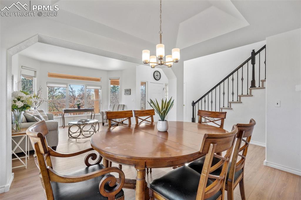 Dining room with light wood-type flooring, a tray ceiling, and a chandelier