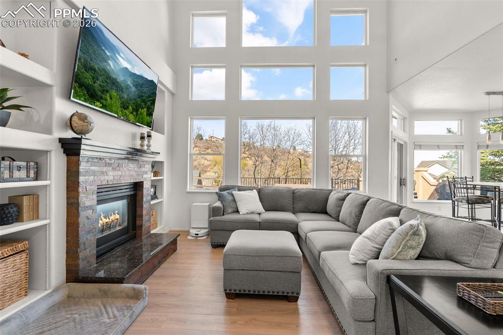 Living area featuring a glass covered fireplace, wood finished floors, a high ceiling, and built in features