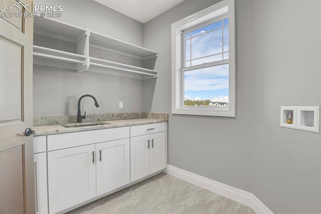 Main level laundtry room w/sink, window and storage