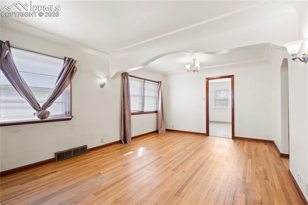 Additional living space with light wood-style floors, a chandelier, and arched walkways