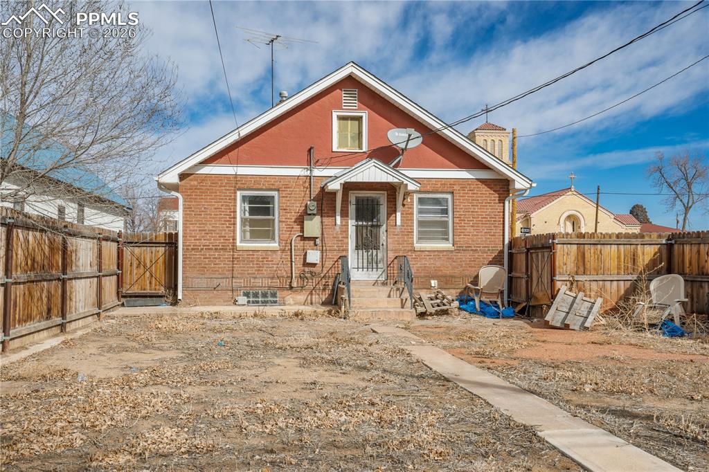Back of property featuring brick siding, a fenced backyard, and a gate