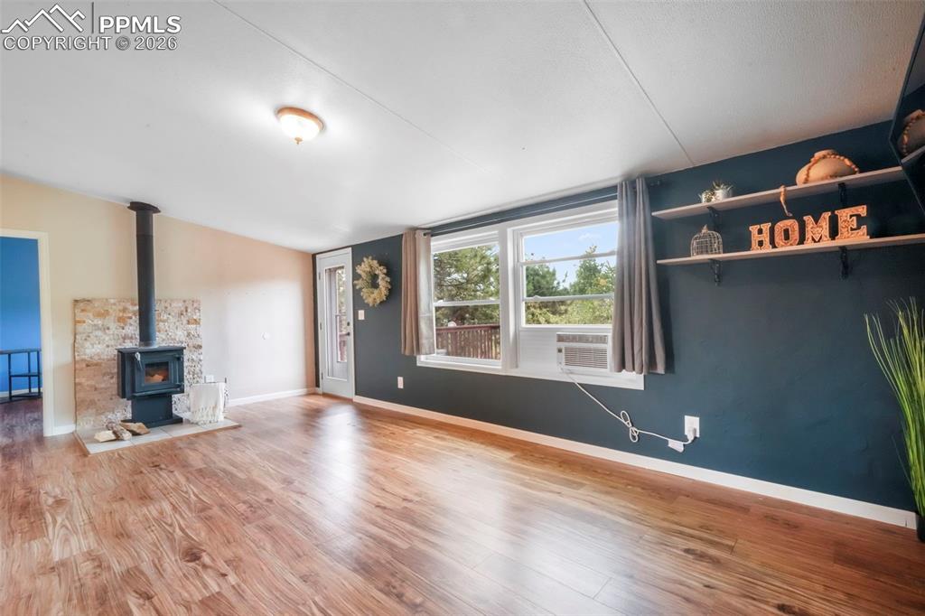 Unfurnished living room with a wood stove and wood finished floors