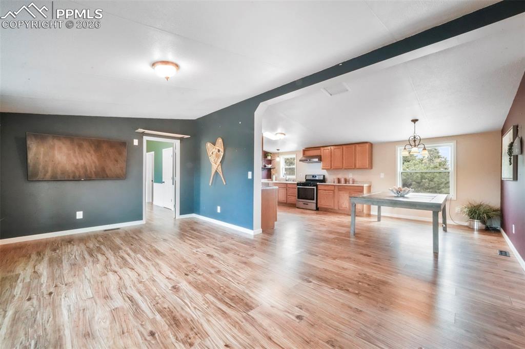 Living room with a barn door, light wood-type flooring, and lofted ceiling