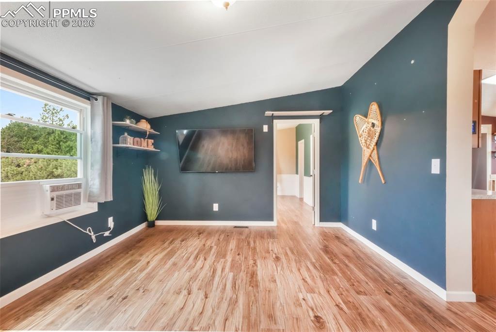 Spare room featuring a barn door, vaulted ceiling, and light wood finished floors