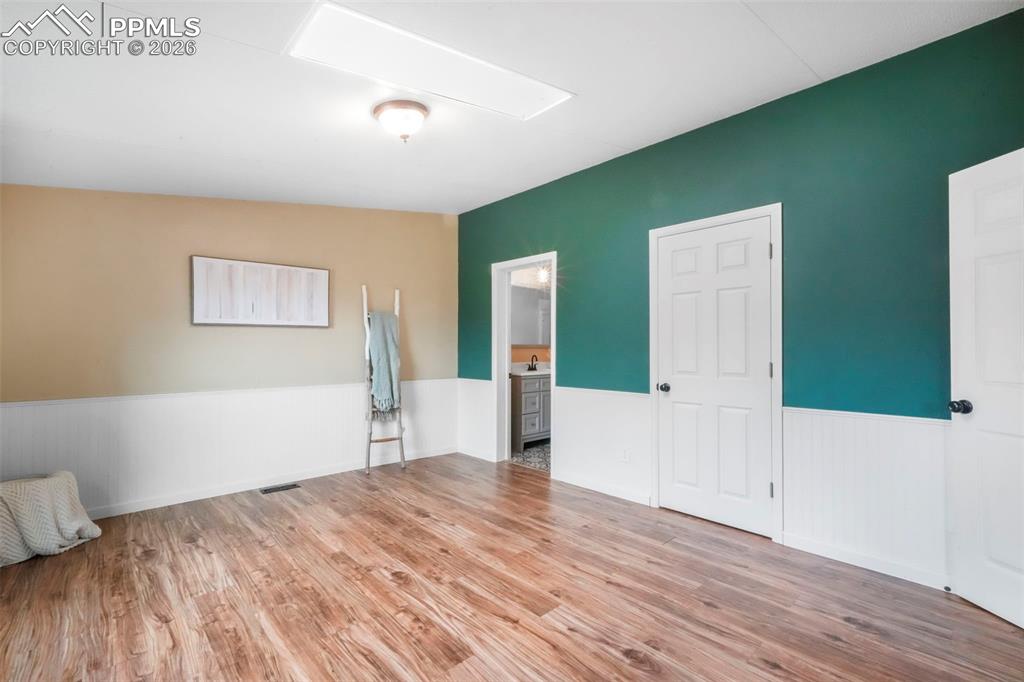 Empty room with light wood-style floors and a wainscoted wall